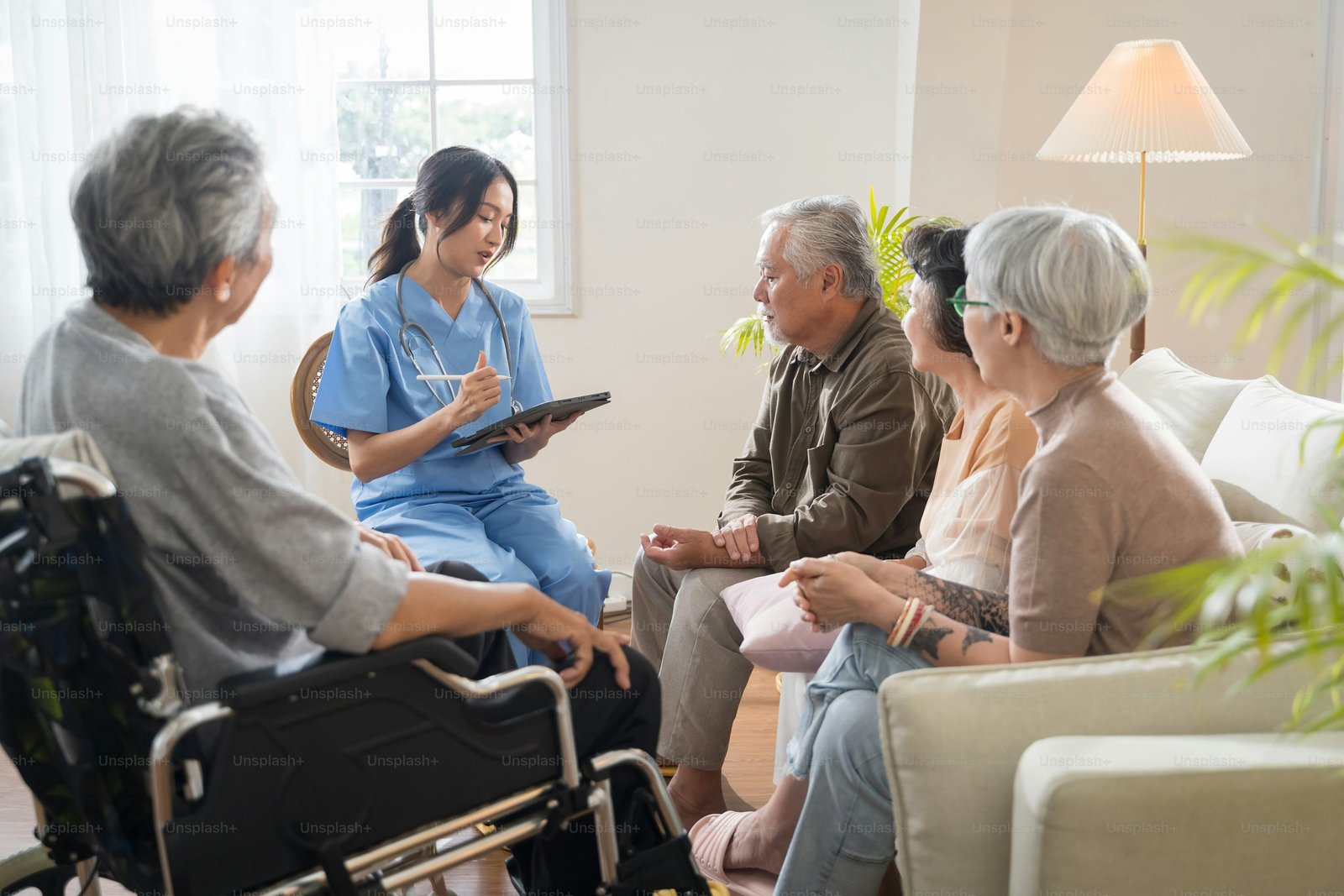 A care worker in conversation with an older man in a sunlit room at home