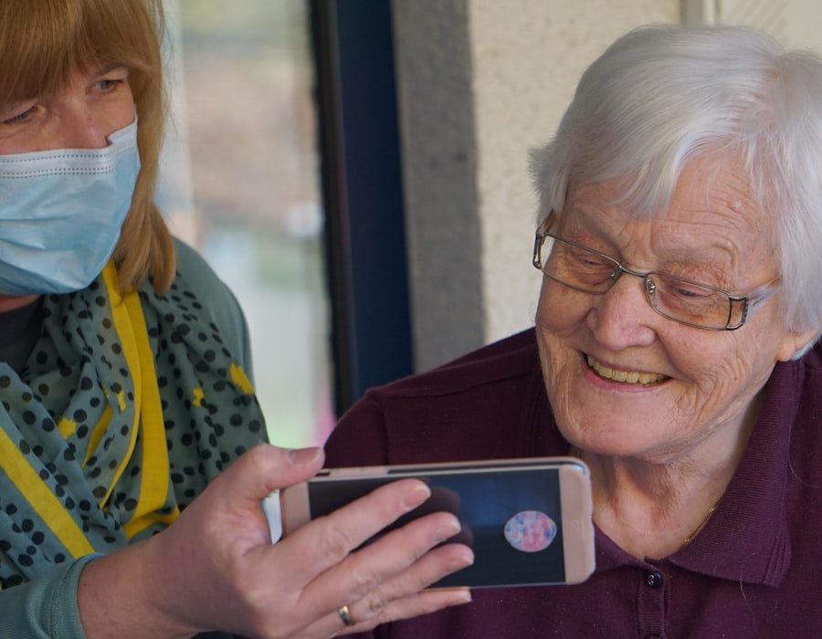 A caregiver showing something on a phone to an elderly woman