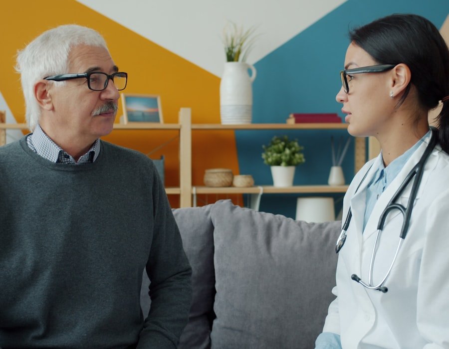 A clinician in conversation with an older man seated at home